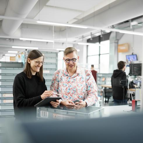 Ein Mitarbeiter und eine Mitarbeiterin von Testo arbeiten gemeinsam am Schreibtisch und blicken gemeinsam in die Kamera.